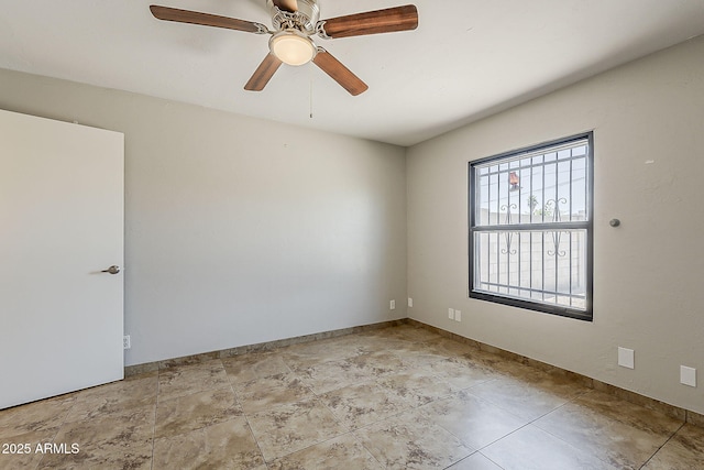 empty room with a ceiling fan and baseboards
