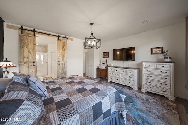 bedroom with dark hardwood / wood-style floors, ensuite bath, a barn door, and an inviting chandelier