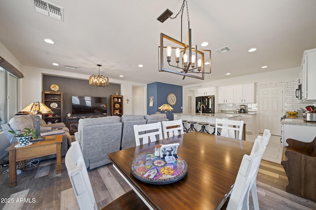 dining room with hardwood / wood-style flooring, sink, and a chandelier