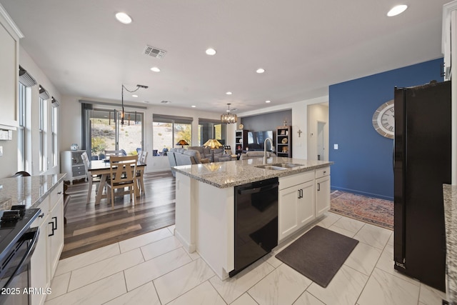 kitchen with black appliances, white cabinetry, an island with sink, sink, and hanging light fixtures