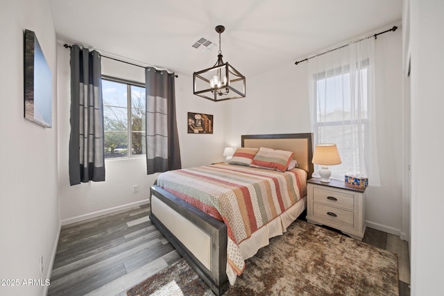 bedroom featuring a chandelier, dark hardwood / wood-style floors, and multiple windows