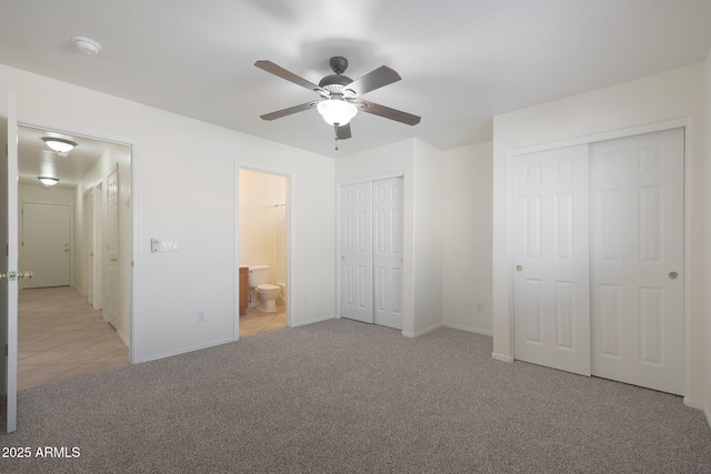 unfurnished bedroom featuring multiple closets, ceiling fan, connected bathroom, and light carpet