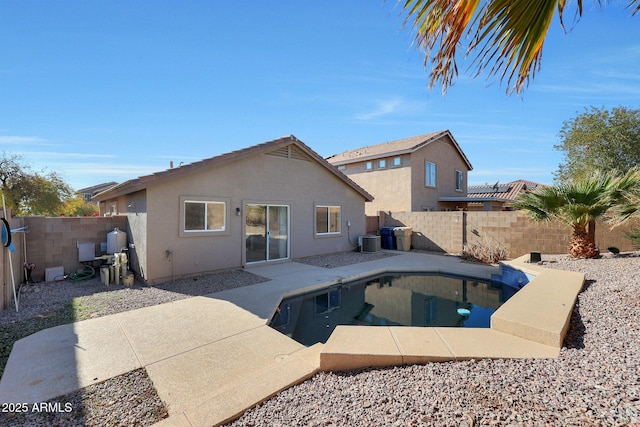 rear view of property featuring a fenced in pool, central AC unit, and a patio area