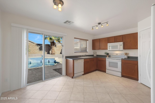 kitchen with sink, light tile patterned floors, and white appliances