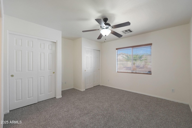 unfurnished bedroom featuring multiple closets, ceiling fan, and carpet floors