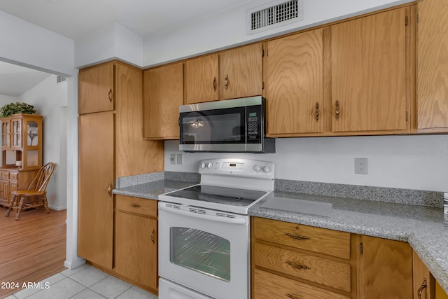 kitchen featuring light stone countertops, electric stove, and light hardwood / wood-style flooring