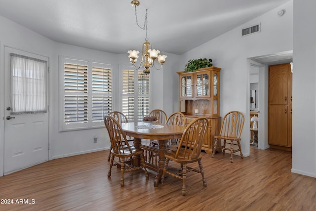 dining space with hardwood / wood-style flooring, an inviting chandelier, and lofted ceiling