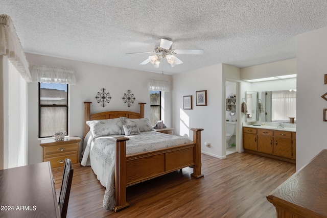 bedroom featuring ceiling fan, sink, ensuite bathroom, a textured ceiling, and hardwood / wood-style flooring