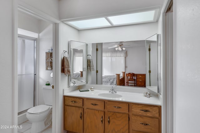 bathroom with a skylight, tile patterned floors, vanity, ceiling fan, and toilet