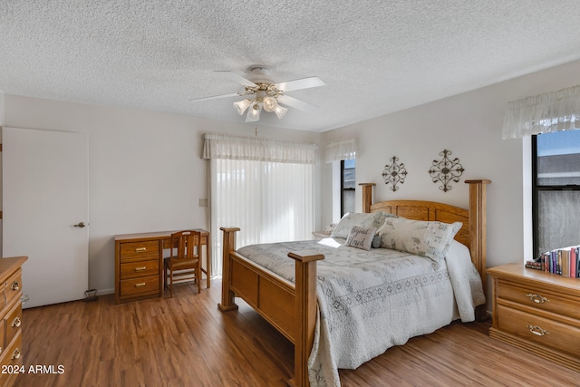 bedroom featuring ceiling fan, wood-type flooring, and a textured ceiling