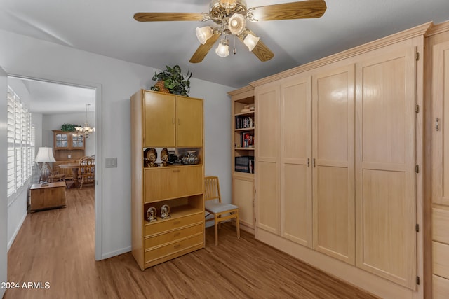 living area featuring light hardwood / wood-style flooring and ceiling fan with notable chandelier