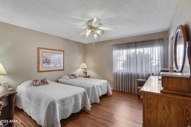 bedroom with hardwood / wood-style floors, a textured ceiling, and ceiling fan