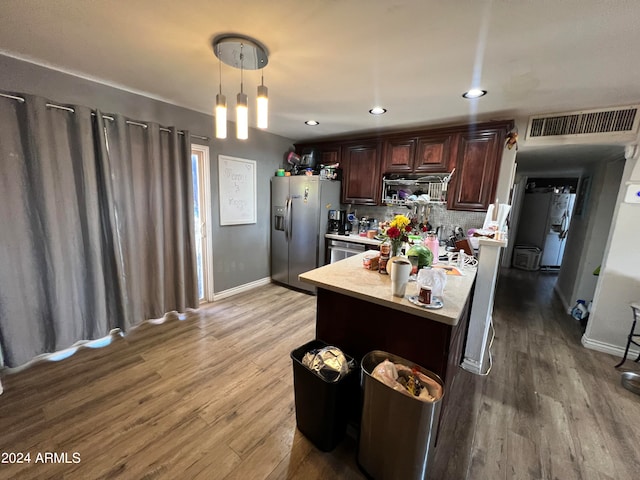 kitchen with pendant lighting, dark brown cabinets, appliances with stainless steel finishes, light wood-type flooring, and decorative backsplash