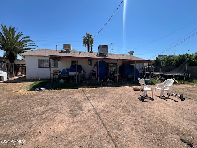 rear view of house featuring a trampoline and central AC unit