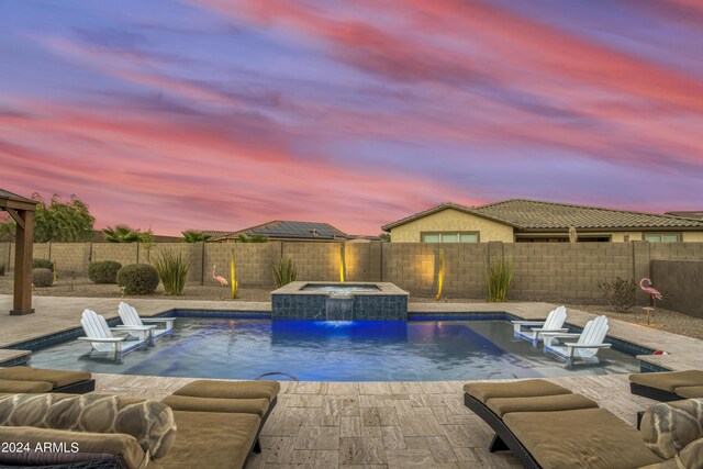 pool at dusk with a patio, a gazebo, an in ground hot tub, and pool water feature