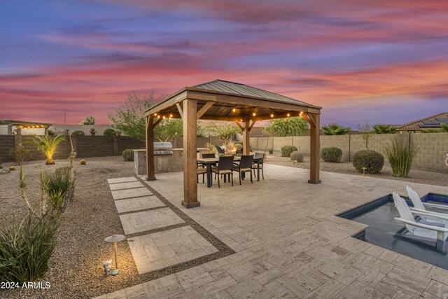 patio terrace at dusk with a gazebo and exterior kitchen