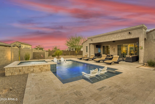 15201 S 183rd Dr, Goodyear, AZ 85338 - pool at dusk with a fenced backyard, a pool with connected hot tub, outdoor lounge area, and a patio area