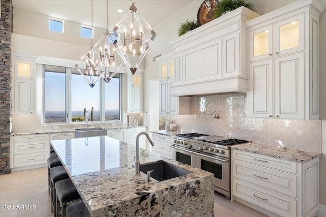 kitchen featuring range with two ovens, hanging light fixtures, lofted ceiling, and sink