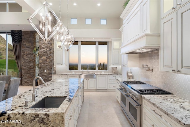 kitchen featuring light stone countertops, decorative backsplash, sink, and double oven range