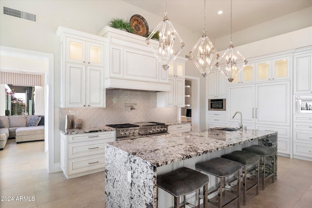 kitchen with white cabinets, appliances with stainless steel finishes, a kitchen island with sink, and a kitchen breakfast bar