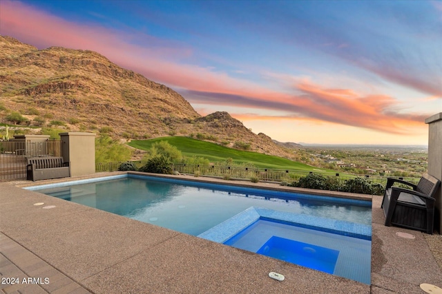 pool at dusk with a mountain view and an in ground hot tub