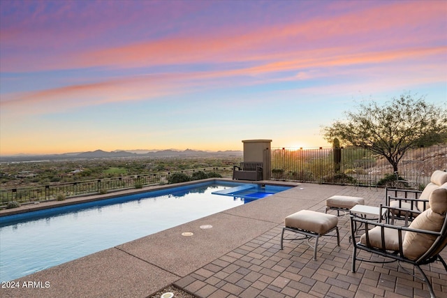 pool at dusk with a mountain view and a patio area