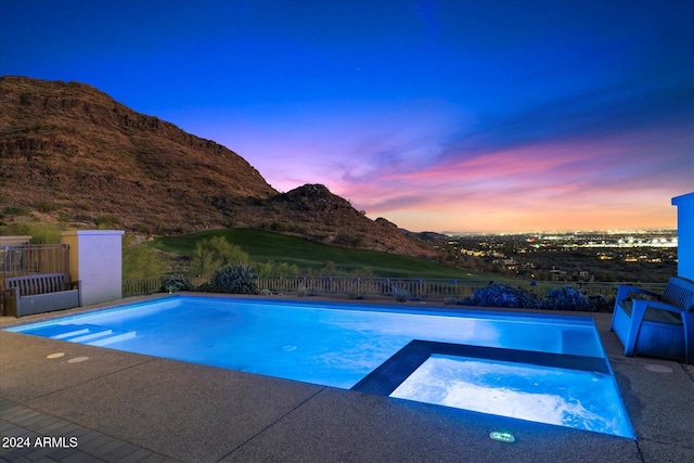 pool at dusk featuring an in ground hot tub and a mountain view