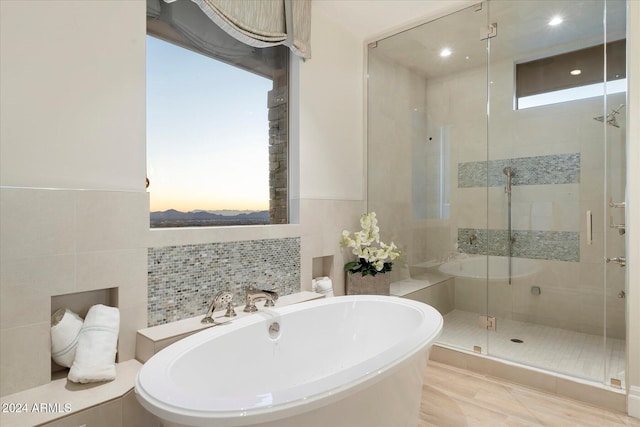 bathroom featuring tile walls and shower with separate bathtub