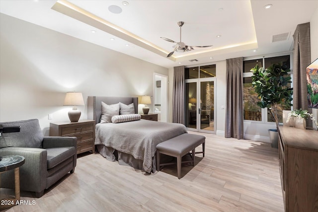 bedroom featuring access to outside, a raised ceiling, ceiling fan, and light hardwood / wood-style flooring