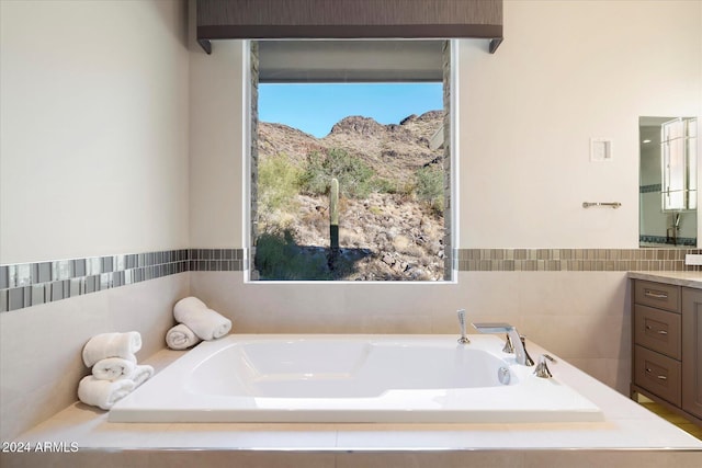 bathroom featuring vanity, a relaxing tiled tub, and a mountain view