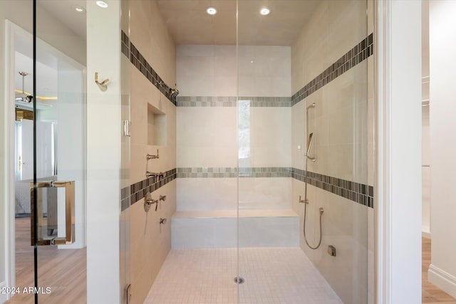 bathroom featuring hardwood / wood-style flooring, an enclosed shower, and tile walls