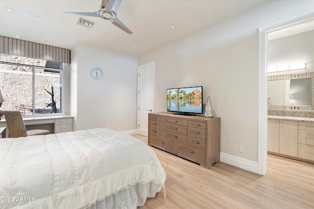 bedroom with light hardwood / wood-style floors, ensuite bath, ceiling fan, and sink