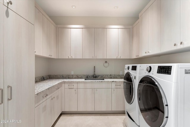 laundry room featuring washer and clothes dryer, sink, and cabinets