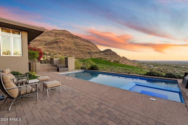 pool at dusk with a mountain view and a patio area