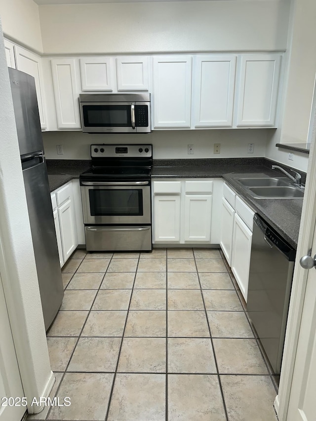 kitchen with sink, light tile patterned floors, white cabinets, and appliances with stainless steel finishes