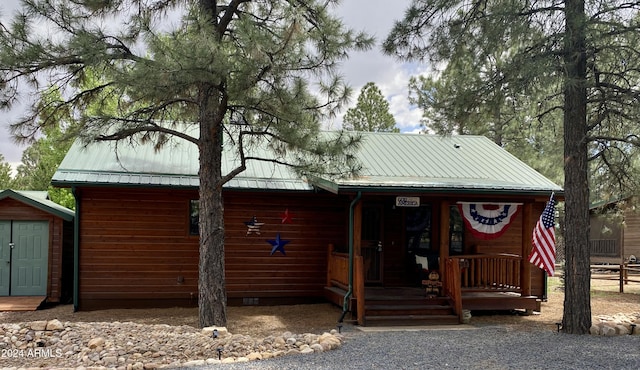 rustic home with metal roof, an outbuilding, crawl space, covered porch, and a shed