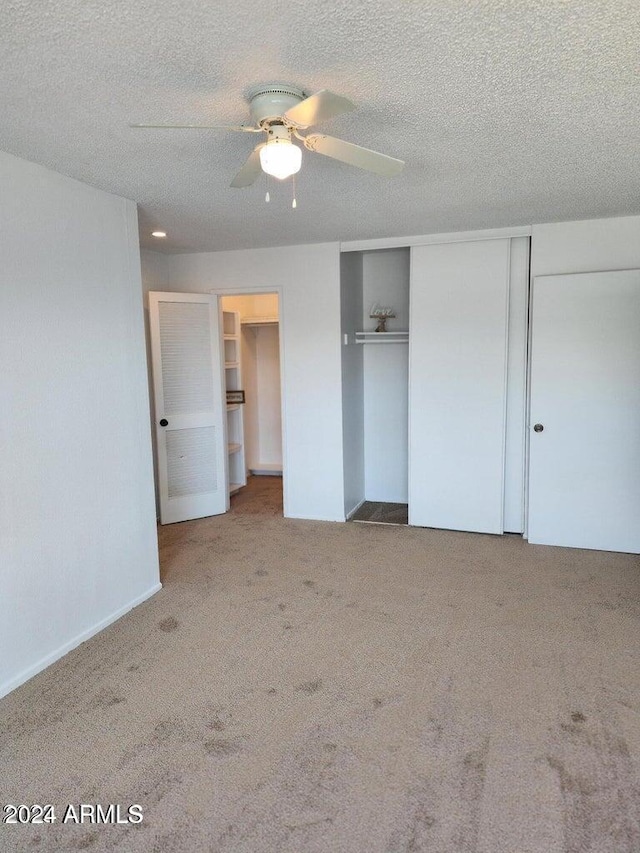 unfurnished bedroom featuring carpet flooring, ceiling fan, a textured ceiling, and a closet