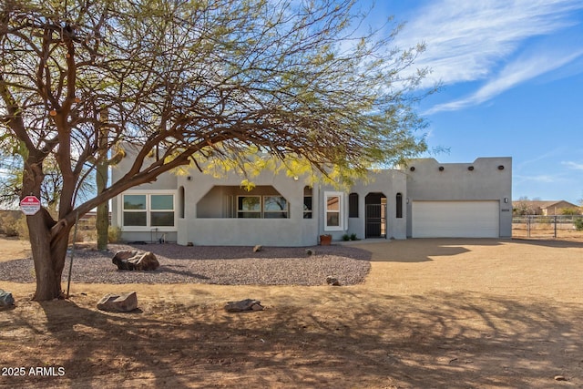 pueblo revival-style home with a garage, driveway, and stucco siding