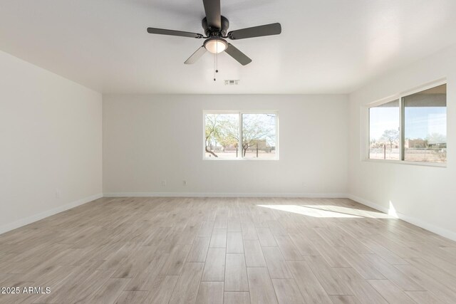 spare room with visible vents, plenty of natural light, light wood-style flooring, and baseboards