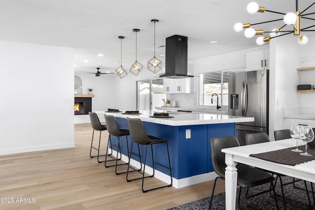 kitchen with a breakfast bar, white cabinetry, island range hood, stainless steel fridge with ice dispenser, and a kitchen island