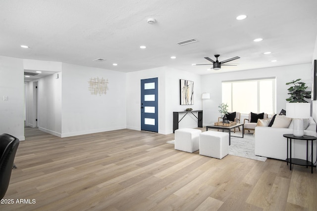 living room featuring ceiling fan, light hardwood / wood-style flooring, and a textured ceiling