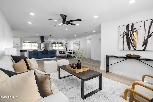 living room with ceiling fan and light hardwood / wood-style flooring