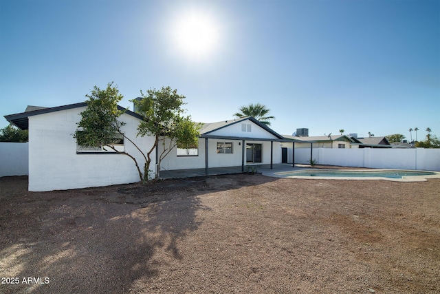 back of property with a fenced in pool and a patio