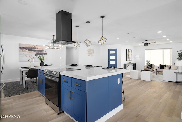 kitchen with stainless steel electric range oven, pendant lighting, island exhaust hood, blue cabinetry, and light hardwood / wood-style flooring