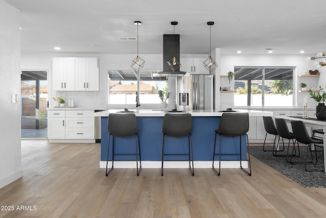 kitchen featuring island exhaust hood, white cabinets, light hardwood / wood-style floors, and decorative light fixtures