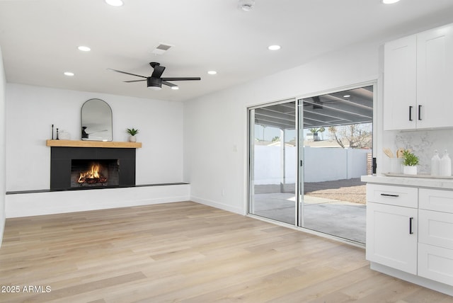 unfurnished living room featuring ceiling fan and light wood-type flooring