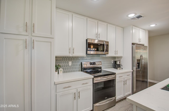 kitchen featuring light stone counters, stainless steel appliances, light hardwood / wood-style floors, backsplash, and white cabinets