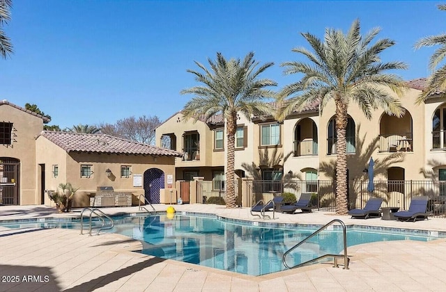 view of pool with exterior kitchen and a patio