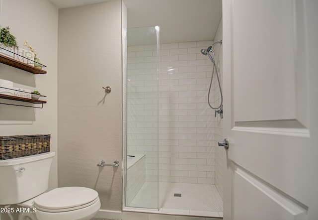 bathroom with toilet and a tile shower