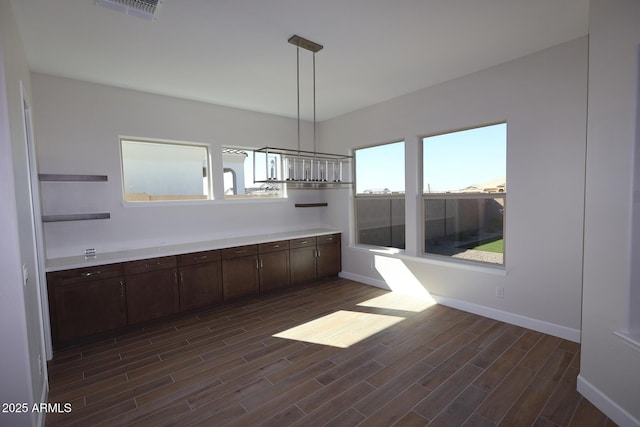 unfurnished dining area with dark wood-style flooring and baseboards